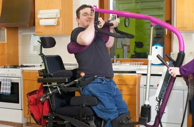 Disabled man using hoist to pull himself out of wheelchair