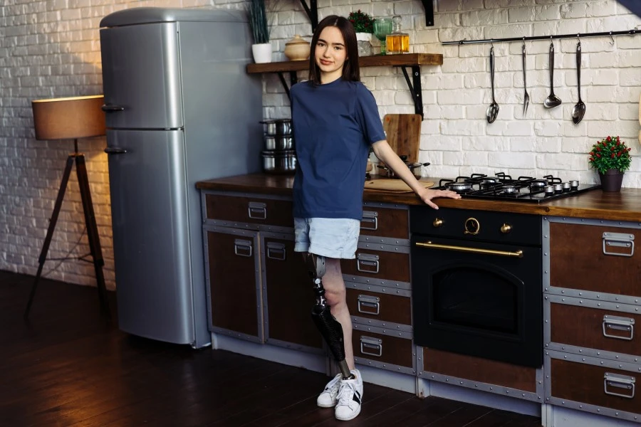 Disabled amputee female standing in kitchen and smiling at camera